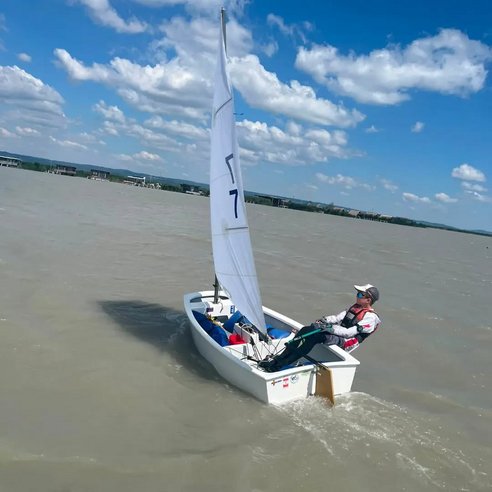 Seglerin auf Jolle mit Segelnummer 7 segelt auf einem See bei Neusiedl am See