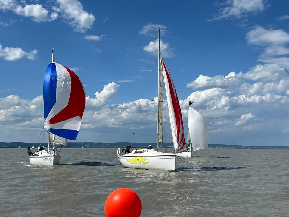 Segelboote mit bunten Segeln auf dem See vor bewölktem Himmel